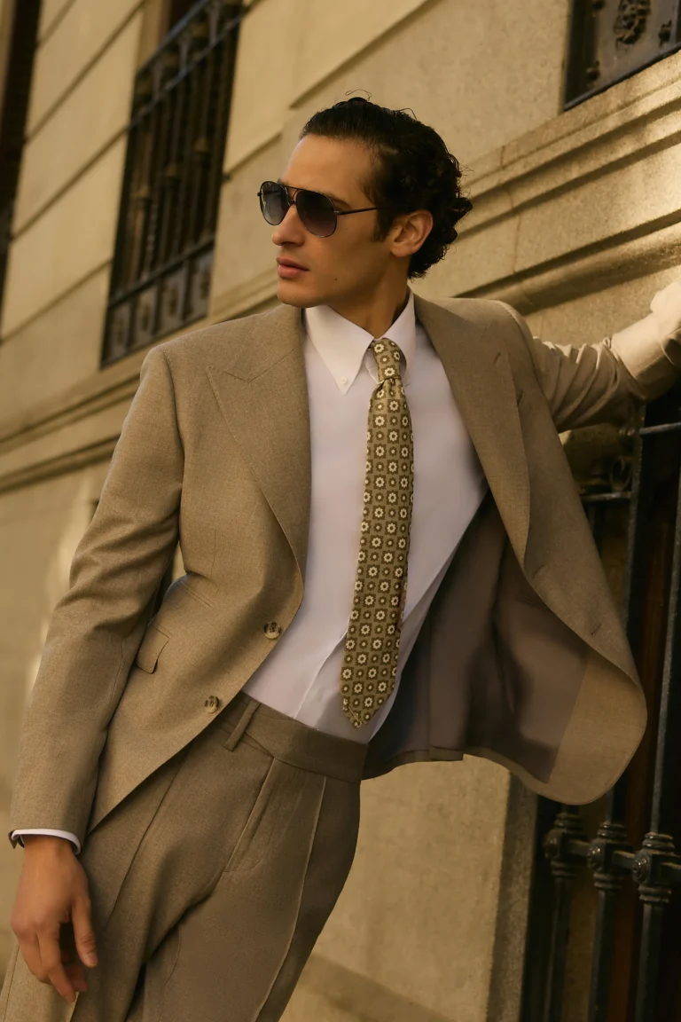 man wearing tan suit leaning against building